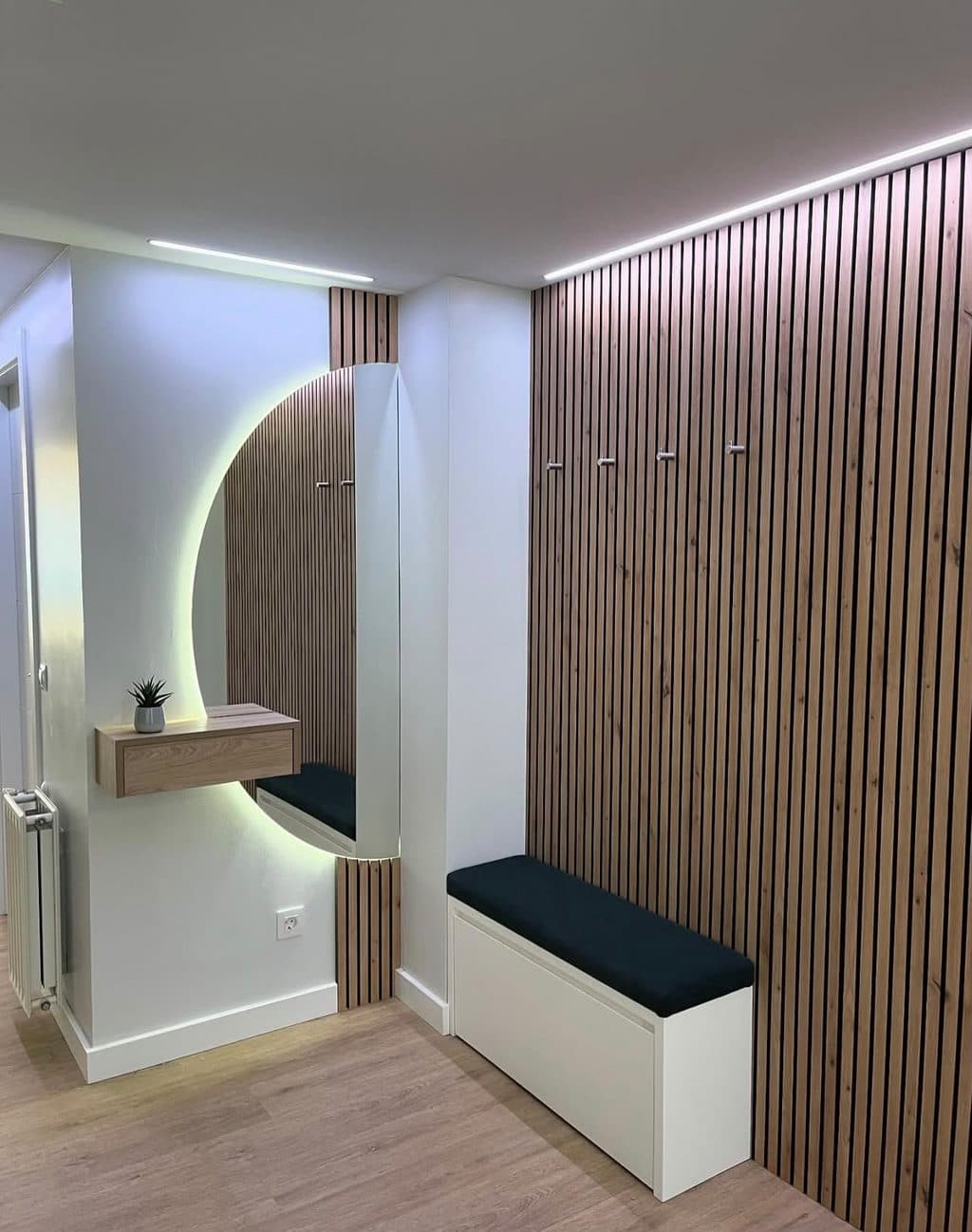 Recibidor con revestimiento de láminas de madera y banco a medida realizado por carpinteros en Santiago